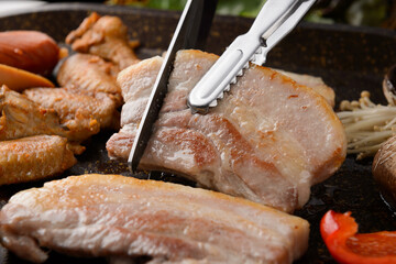 Cutting grilled pork belly with scissors
