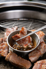 Grilled pork being dipped in sauce
