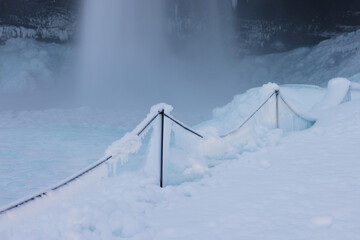 Frozen Railing Near Waterfall Surrounded by Ice and Snow