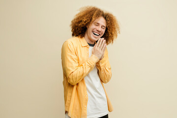 Young man with frizzy hair laughing with hands clasped together