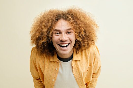 Young man with frizzy hair smiling and expressing happiness