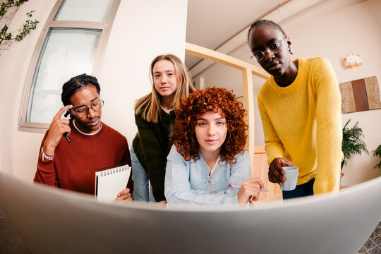 Employees looking at a computer while discussing at a shared desk