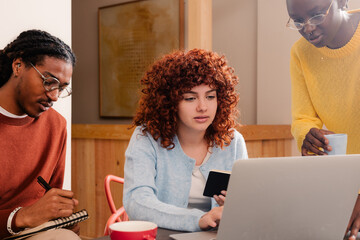 A meeting of office workers around a laptop at a work table