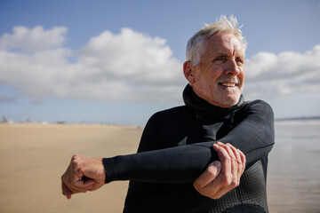 Senior Man Stretching on Sandy Beach During a Sunny Day