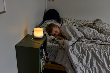 Little boy sleeps in bed with humidifier on 