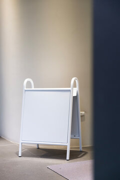A blank white board sign stands ready for message in a minimal setting
