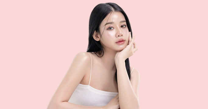 Glowing skin make up style of beautiful young Asian model isolated on pink background.