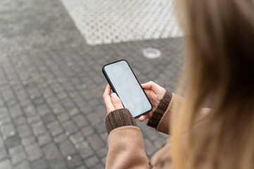 Woman using smartphone with blank white screen outdoors