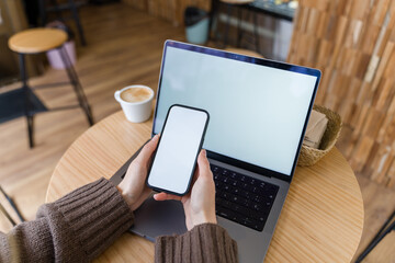 Woman using laptop and smartphone with blank mockup screen 