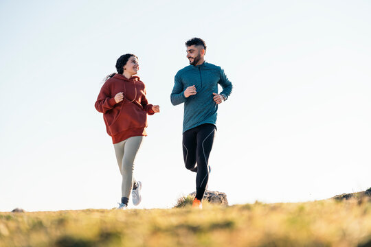 Happy couple running outdoors in countryside on sunny day
