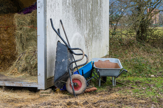 Straw and hay bales next to wheelbarrows on a farm