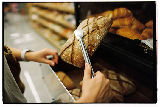 Anonymous faceless woman buying bread at the supermarket, close up