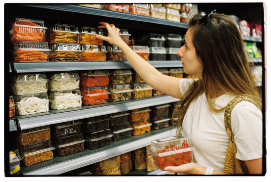Woman picking dried fruit and nuts at the supermarket, film close up
