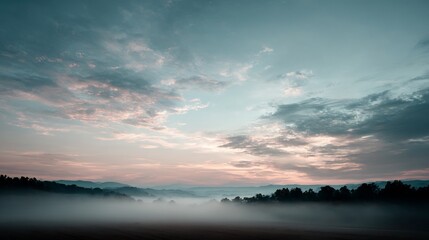 Serene landscape with fog-covered field under a pastel-colored sky at sunrise