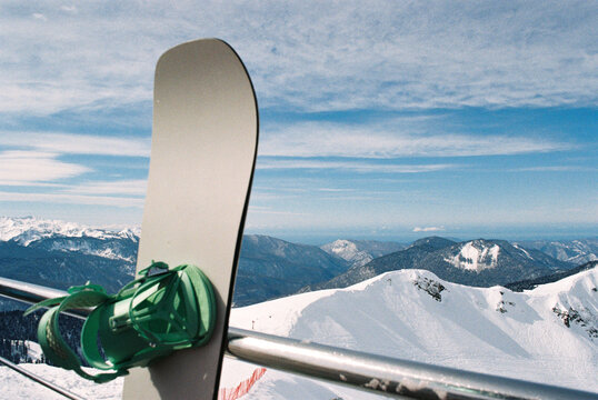 Snowboard with green bindings on mountain peak 