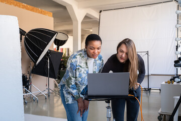 Photographer And Client Analyzing Results Of Photoshoot In Studio
