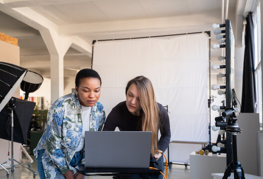 Photographer And Client Looking At Laptop In Studio