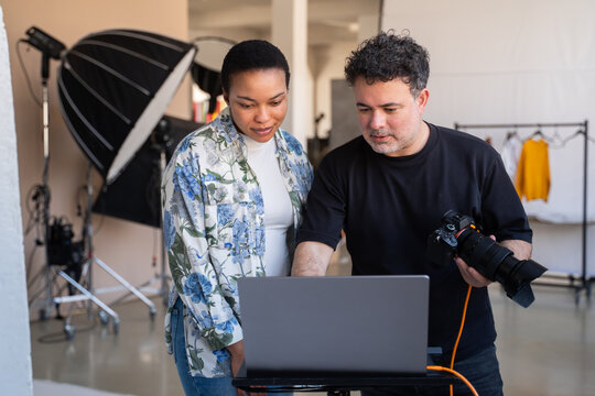 Photographer And Client Looking At Results Of Photoshoot In Studio