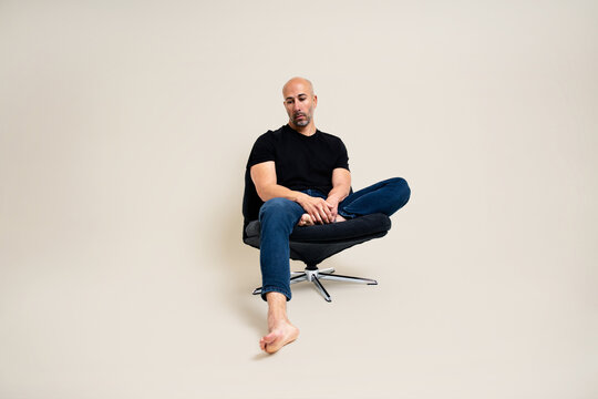  Man sitting cross-legged on a black swivel chair