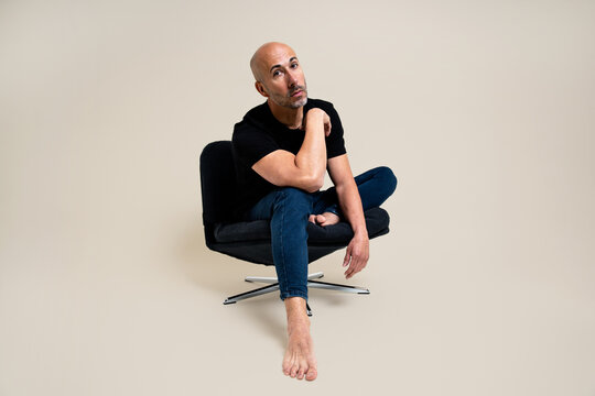  Man sitting cross-legged on a black swivel chair
