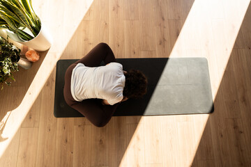 Woman practicing child's pose yoga on mat in studio with plants