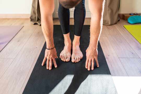 Man practicing yoga forward bending pose on mat