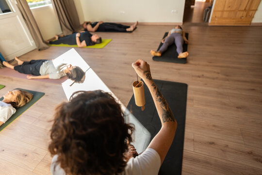 Yoga instructor using koshis during group relaxation session in studio