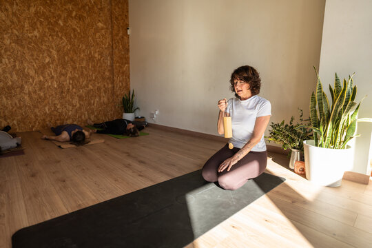 Yoga instructor playing koshi chime during relaxation in studio