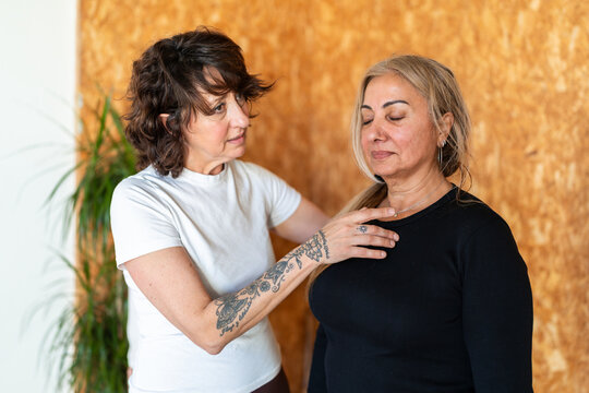 Yoga instructor guiding mature woman in breathing exercise