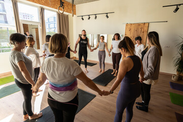 Group of people holding hands during relaxing therapy and yoga session