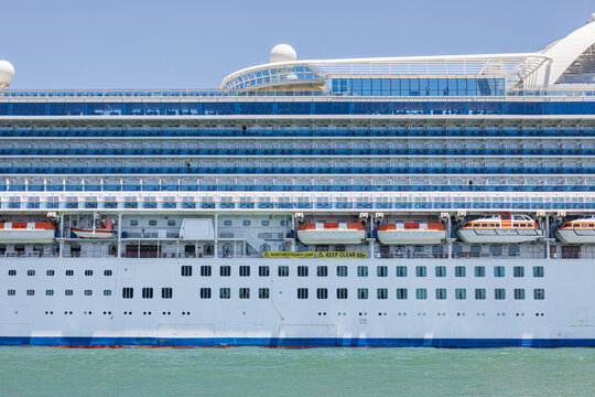 Large cruise ship docked with panoramic decks and lifeboats