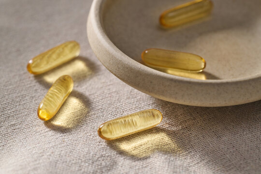 Golden omega-3 capsules sit near a simple bowl