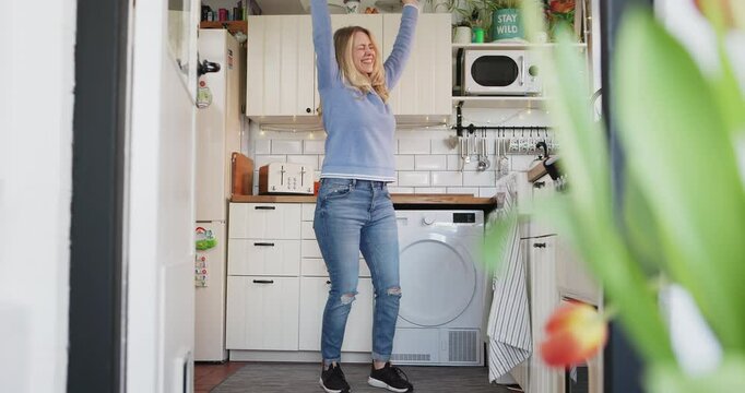 Dance, happy woman in kitchen and excited in new home with fun, freedom and music in Germany. Happiness, celebrate and girl dancing in apartment with smile, wellness mindset and positive time alone.