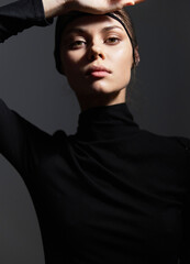 Stylish woman in a black turtleneck striking a pose with a confident expression, exhibiting modern fashion and minimalistic aesthetics. © SHOTPRIME STUDIO