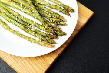 Grilled asparagus spears served on a white plate with sesame seeds