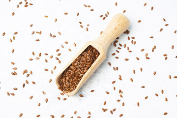 Flax seeds in a wooden scoop on white background