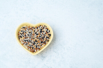 Mixed grains in heart-shaped bowl on a light background