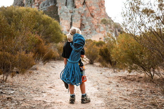 young climber with coiled rope on his back