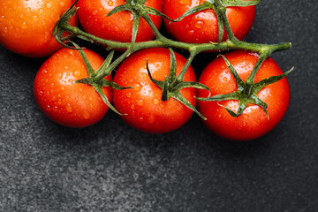 Fresh tomatoes with droplets on black surface