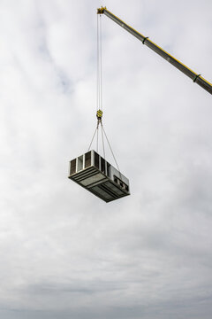 A crane lifts a large heating, ventilation and air conditioning (HVAC)
