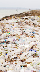 Plastic bottle pollution scattered across shore shows beach litter, ocean trash, dirty coastline, water contamination, environmental crisis and climate disaster