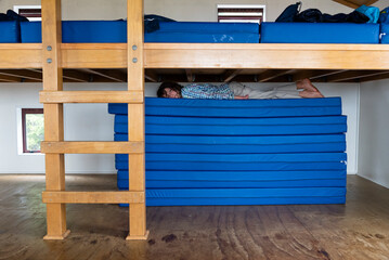 Young boy playing on mattresses at a mountain hut, New Zealand.