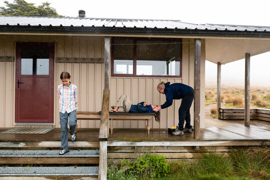 Mother washing boys outside a hut, New Zealand. 