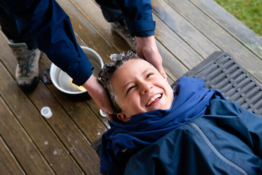 Mother washing boys outside a hut, New Zealand. 