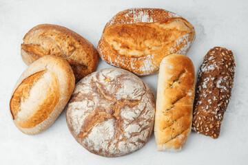Various types of freshly baked bread displayed on a white surface