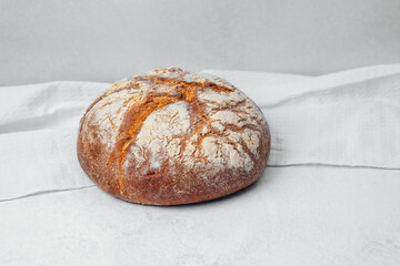 Freshly baked round artisanal bread on a light textured cloth