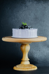 Delicious cake with blueberry topping on wooden stand in studio setting