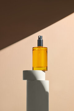 A yellow elegantly perfume bottle  against a beige background
