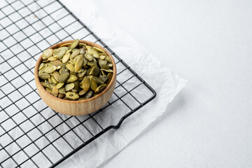 Bowl of pumpkin seeds on cooling rack in well-lit kitchen setting
