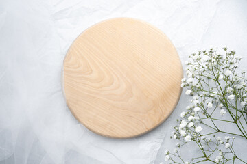 Elegant wooden circle with delicate white flowers on soft background